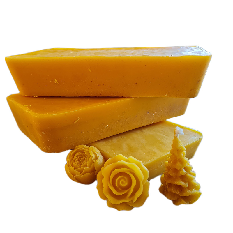 Three plastic tubs filled with golden beeswax blocks and carved wax shapes