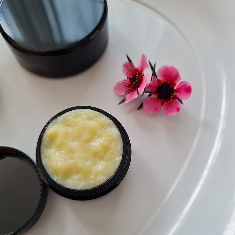 Open jar of creamy royal jelly with pink flowers